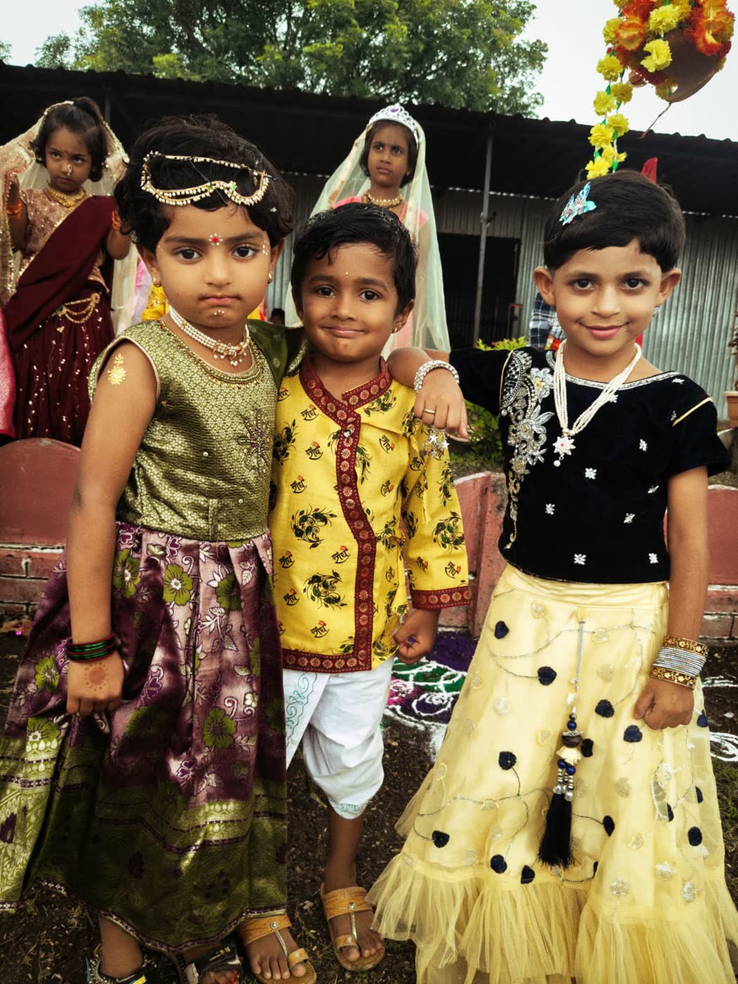 Three young children in festival clothes, smiling