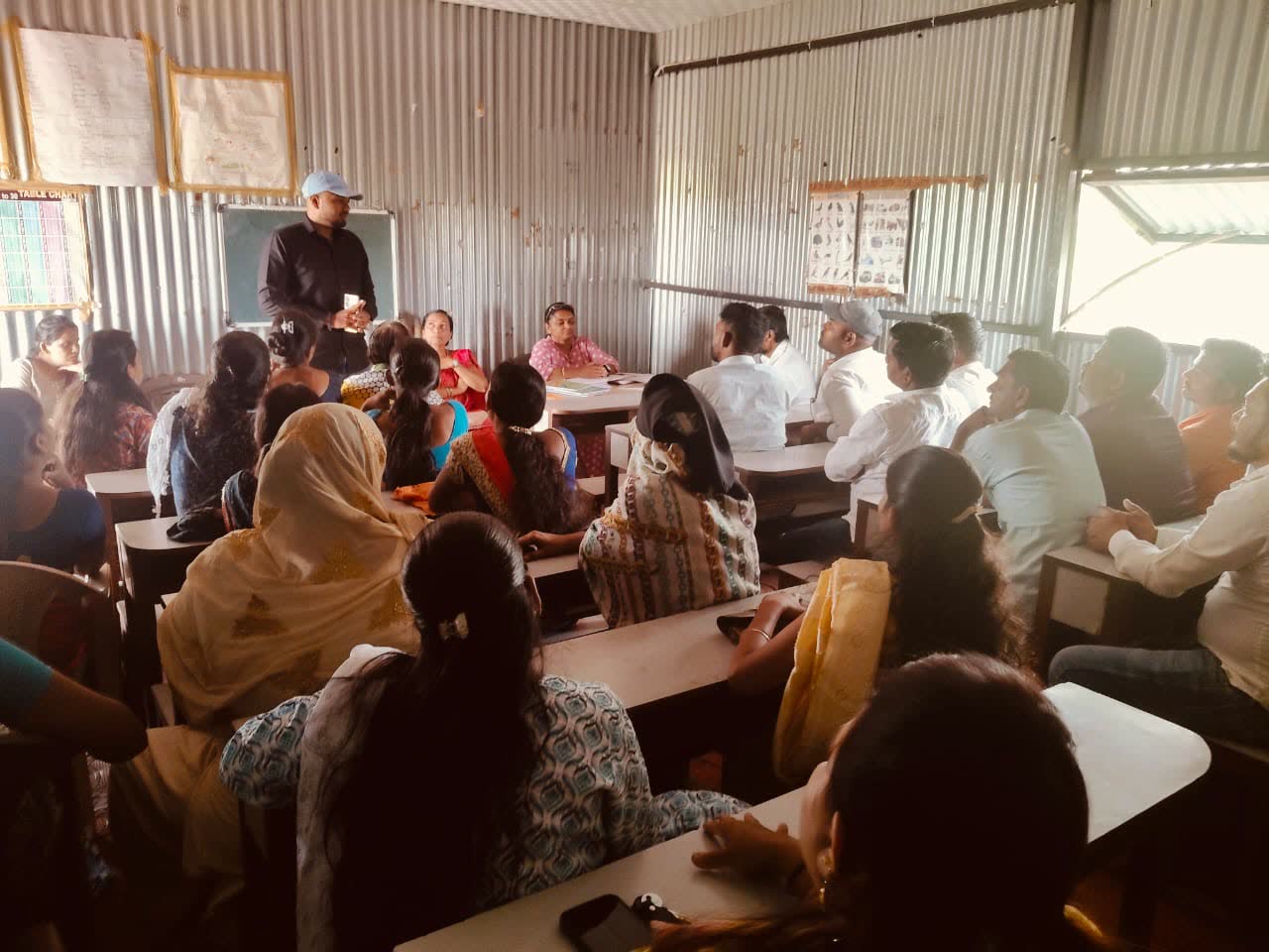 Parents seated at desks in a classroom during a parents' meeting