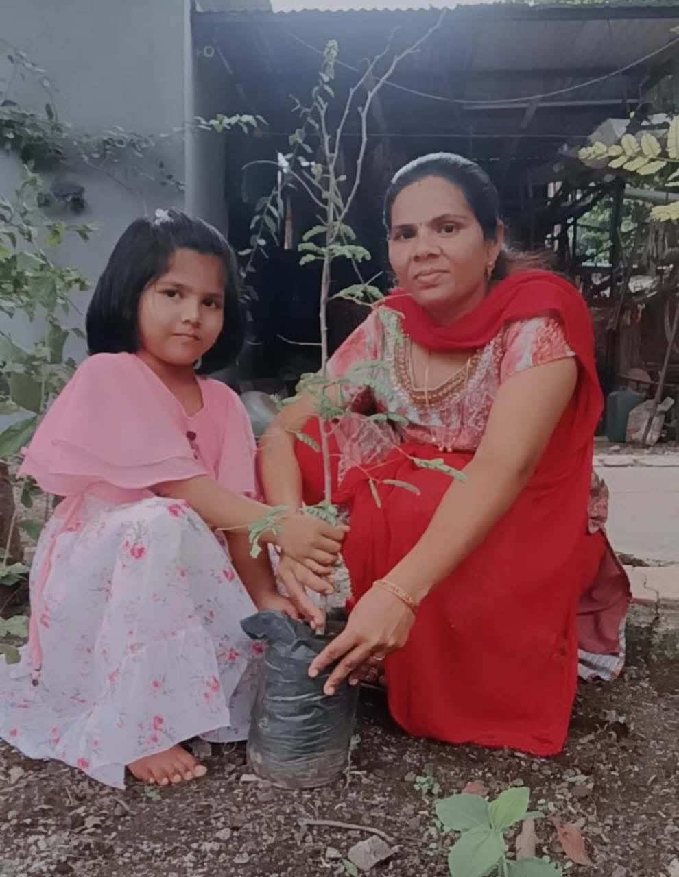 A girl and her mother planting a sapling together